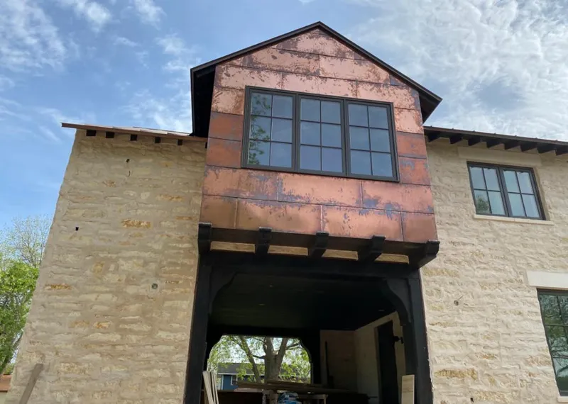 Copper metal panel facade on a stone building for Roof Repair in Marshalltown