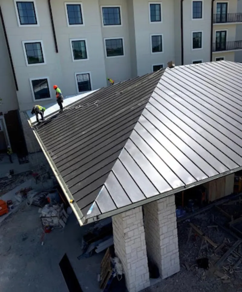 Crew installing standing seam metal roof panels on a commercial project in Marshalltown